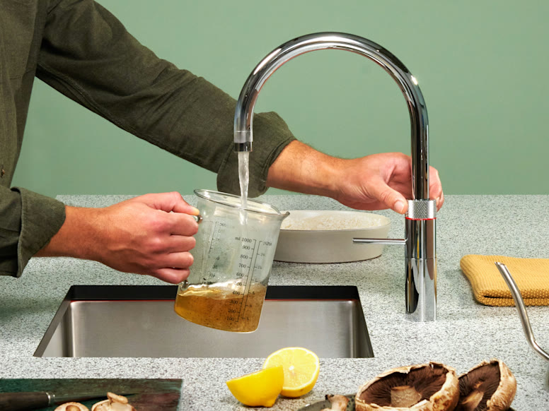 Pouring boiling water from a chrome Quooker Fusion Round into a measuring jug to make stock